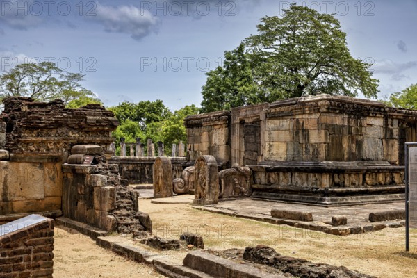 Old stone buildings in a ruined site with trees and blue sky in the background, The temples of Polonnaruwa in Sri Lanka