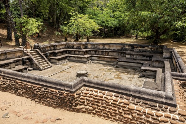 Water basin framed by stones in a wooded setting when the sun is shining, The temples of Polonnaruwa in Sri Lanka