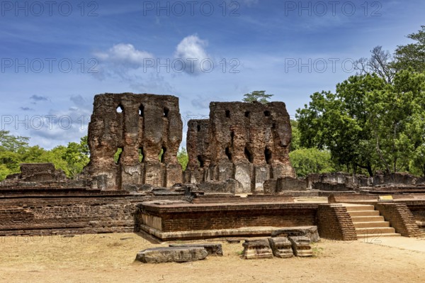 Tall brick ruins with multiple openings under a cloudy sky surrounded by trees, The temples of Polonnaruwa in Sri Lanka