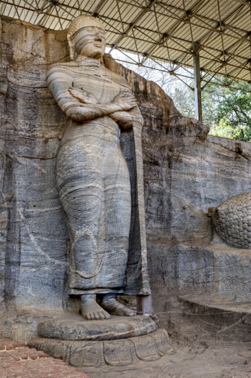 Standing rock statue with detailed texture and ancient appeal under a canopy, The Buddhas near Polonnaruwa in Sri Lanka