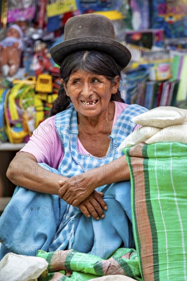 A woman in traditional clothing and hat sits quietly at a market, the Rurrenabaque market in Bolivia