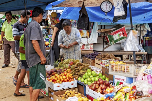 Fruit and vegetables in boxes at a market stand where customers look around and shop, The Rurrenabaque market in Bolivia