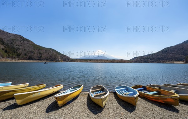 Rowing boats on shore, view across the lake to Mt Fuji volcano, Motosu Lake, Yamanashi Prefecture, Japan