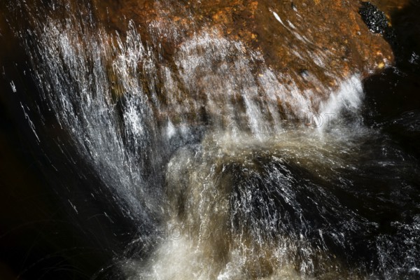 Stream flow with dark water, reflections and turbulences, long exposure, Sweden