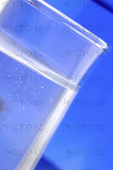 Glass with mineral water, small carbonated pearls on the edge of the glass, drinking water