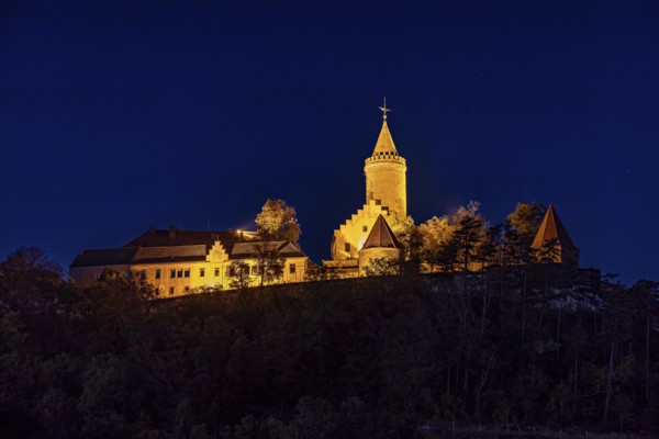 Illuminated castle at night, on a hill, surrounded by shadows and a bright blue night sky, The Leuchtenburg near Kahla im Saale Holzlandkreis in Thuringia