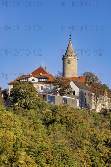 A castle with a distinctive tower, surrounded by colorful autumn trees against a clear sky, The Leuchtenburg near Kahla im Saale Holzlandkreis in Thuringia