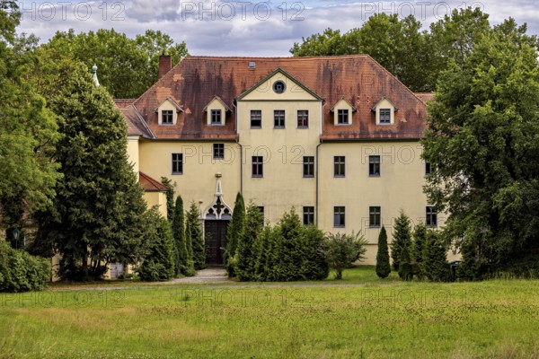 Yellow castle with distinctive roof and well-kept garden surrounded by trees, The Hummelshain hunting lodge in Thuringia