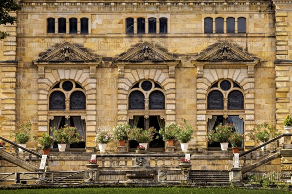 Detail of the castle façade with lush flowers in pots in front of large windows, The Hummelshain hunting lodge in Thuringia