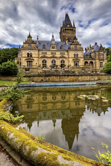 Impressive castle reflected in a quiet pond, cloudy sky above, The Hummelshain hunting lodge in Thuringia