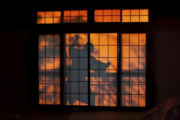 Shadow of a man, burglar with knife, assassin, ninja, on the balcony behind sliding shoji doors in a traditional Japanese house, Yamanouchi, Nagano, Japan