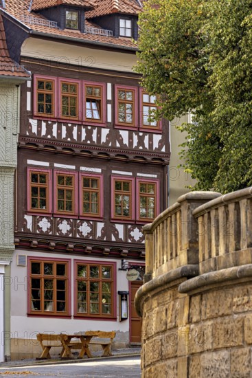 A half-timbered house with red window frames next to a stone wall in a historic town, The old town of Arnstadt in Thuringia