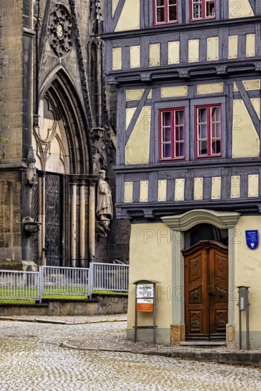 Detailed view of a church portal next to a half-timbered house, paved street in front of it, the old town of Arnstadt in Thuringia