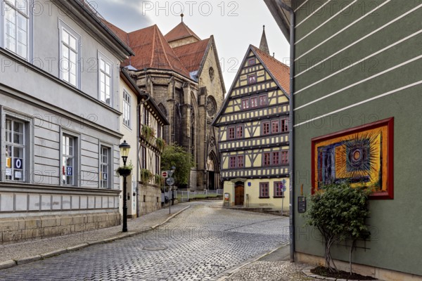 Atmospheric alley with half-timbered houses, church in the background and evening lighting, the old town of Arnstadt in Thuringia