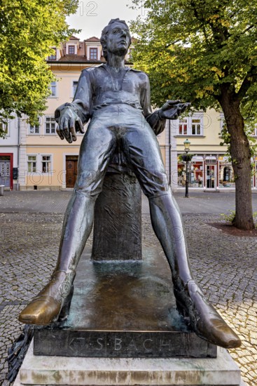 Statue of a smiling man in a square with buildings, Johann Sebastian Bach monument in the old town of Arnstadt in Thuringia