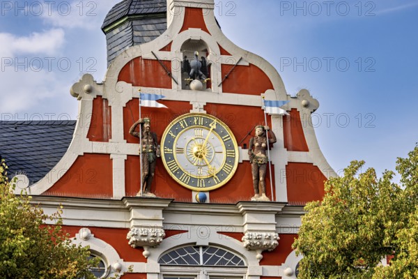 Baroque town hall façade with clock and sculptures in orange on a clear day, The old town of Arnstadt in Thuringia