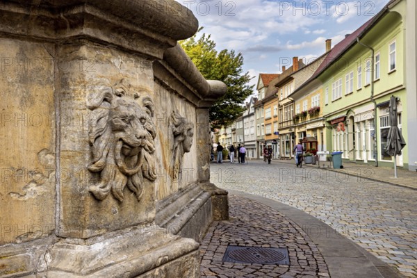 A stone lion relief in a historic old town with cobblestone streets, lion head at the fountain in the old town of Arnstadt in Thuringia