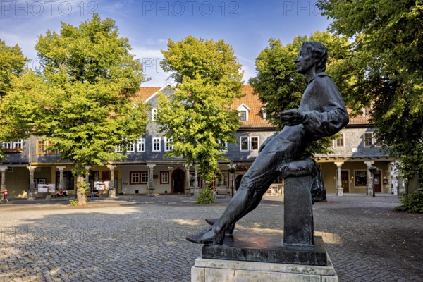 Bronze statue of a man on a paved square with trees, Johann Sebastian Bach monument in the old town of Arnstadt in Thuringia