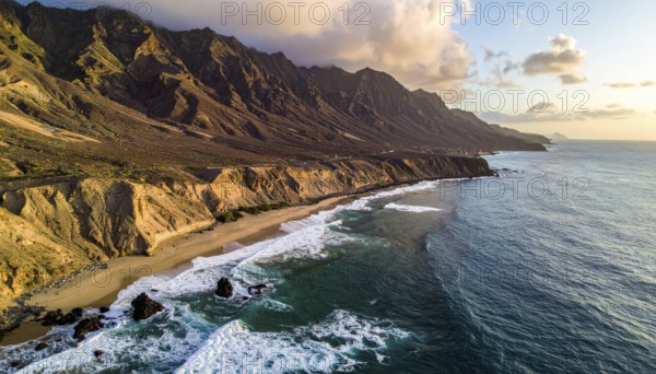 Desert landscape converges with ocean along a rugged coastal area, shore break at cliffs, blue cloudy sky at sunset, dry landscape in an aerial drone view, AI generated