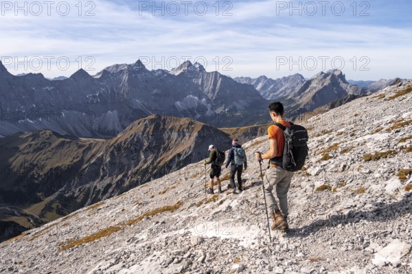 Hikers on the summit ridge of the Gamsjoch, behind rock faces of the Laliderer Spitze, eastern Karwendel, Tyrol, Austria