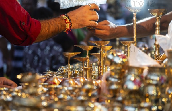 People shop for bronze and other metal items at a roadside stall on Dhanteras, in Guwahati, Assam, India on 18 October 2025. On Dhanteras, people traditionally buy precious metals like gold, silver, or even new utensils, as it is believed this brings wealth and good luck into the household
