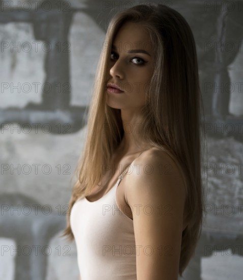 Gorgeous sexy blonde in beige body posing by a gray stone wall shot in new studio