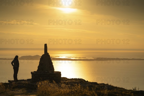 Woman standing next to cairn and looking at the sea, Rørsethornet stone staircase, with 3292 steps one of the longest continuous stone staircases in the world, Sherpat stairs or Midsund stairs or Midsundtrappene, Rørsethornet hike, evening mood, Otroya or Otrøya island, Møre og Romsdal, Norway