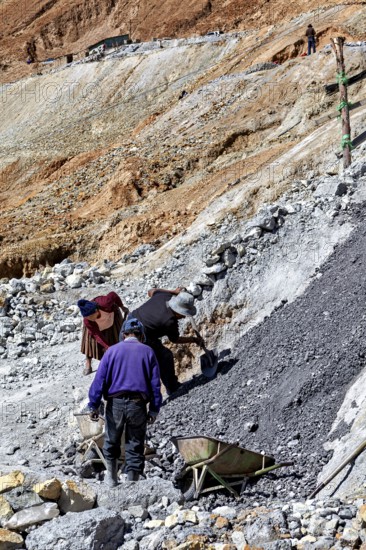 Workers bend on a rocky slope while loading gravel into wheelbarrows, The silver mines of Potosi Bolivia