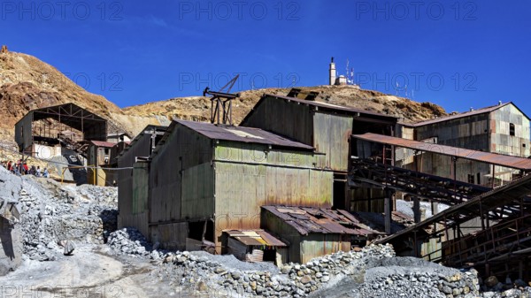 Weathered metal industrial buildings on a mountainside under a clear blue sky, The silver mines of Potosi Bolivia