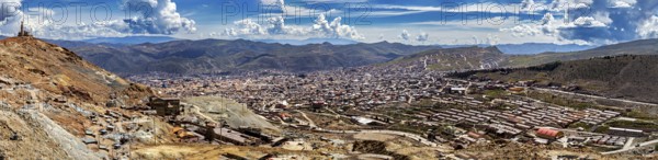Expansive panorama of an urban landscape embedded in mountainous surroundings under a blue sky, view from Silver Mountain Cerro Rico to Potosi in Bolivia