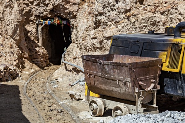 A mine car and a machine near the entrance of a rocky mine, The silver mines of the Cerro Rico silver mountain near Potosi in Bolivia