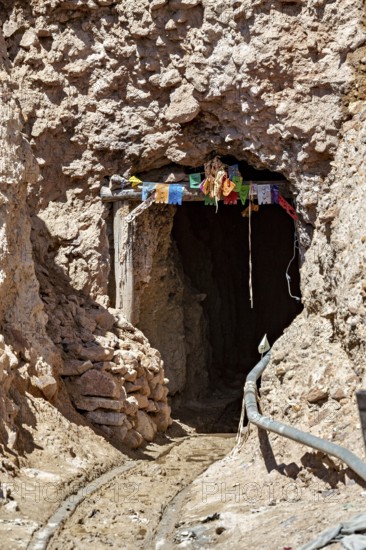 Mine entrance in a rocky landscape decorated with colourful flags, The silver mines of the Cerro Rico silver mountain near Potosi in Bolivia