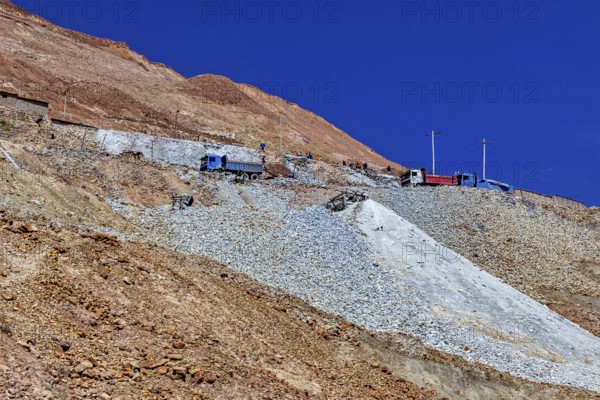Lorries parked on the slope of a rocky mountain under a clear blue sky, The silver mines of the Cerro Rico silver mountain near Potosi in Bolivia