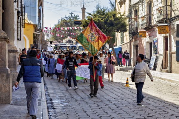 People demonstrate with flags and banners on a cobbled street between historic buildings, demonstration in the streets of Potosi Bolivia