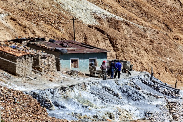 Miners in front of a house with wheelbarrows in a rocky landscape with railings, The silver mines of Potosi Bolivia