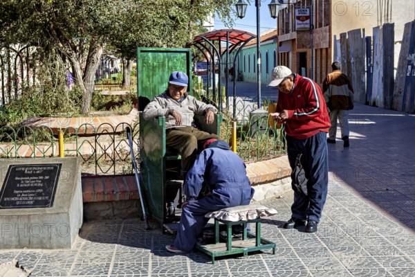 Relaxed street scene in the marketplace with men shining shoes and interacting socially, show shiners in the town of Uyuni in the Salar de Uyuni in Bolivia