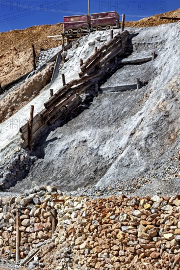 A lonely mine car stands on a rocky slope, surrounded by staggered layers of rock and wooden beams, mining lorry at the Cerro Rico silver mountain near Potosi Bolivia