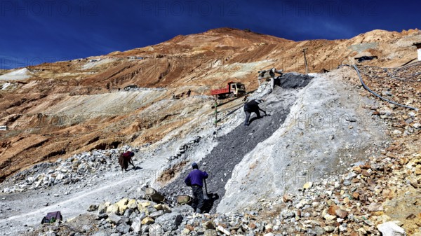 Scene of labourers working on a steep, stony slope under a blue sky, The silver mines of Potosi Bolivia
