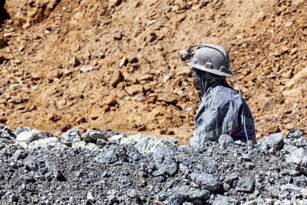 A miner gazes into the distance, surrounded by rocks and dusty terrain, The miners of the Cerro Rico silver mountain near Potosi Bolivia