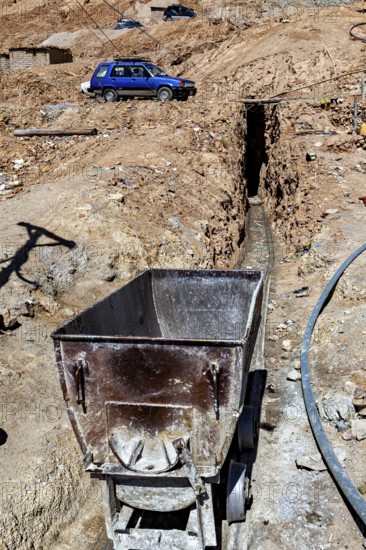 An old mining wagon stands next to a trench in an arid landscape, The silver mines of Potosi Bolivia