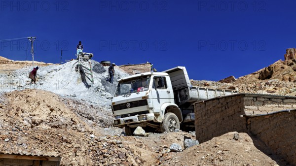 A lorry unloads gravel at a construction site in a mountainous desert landscape under a clear sky, The silver mines of Potosi Bolivia