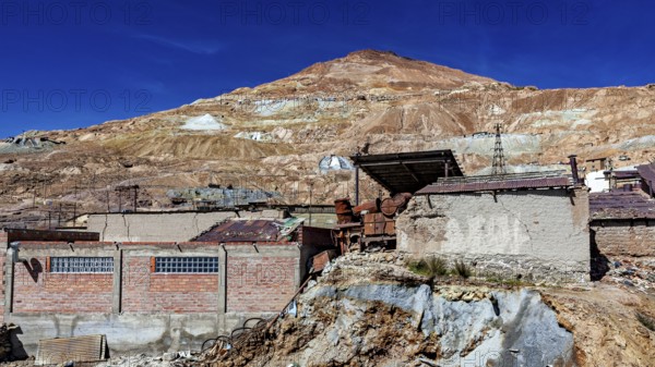 Abandoned mine buildings in front of a barren hill and clear sky, The silver mines of Potosi Bolivia