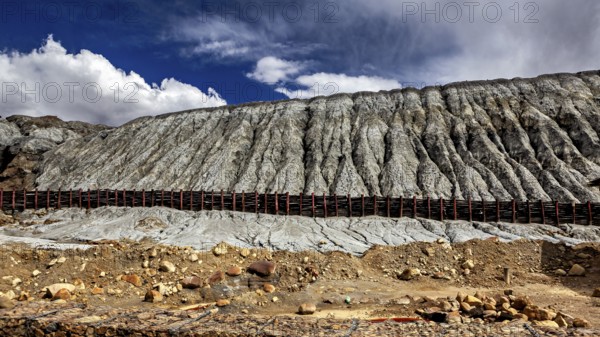 Steep rock faces in a barren desert landscape with clouds in the sky, spoil heap of the silver mines in Potosi Bolivia