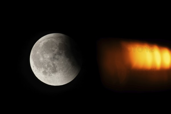 After a total lunar eclipse, the moon appears shortly after its rise in the evening sky as a so-called blood moon in front of it then begins to emerge from the Earth's umbra, Frankfurt am Main, Hesse, Germany