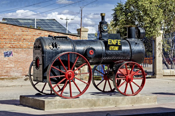 Old steam engine with red wheels stands on a pedestal in the open air in Bolivia, Old historic steam locomotive in Uyuni in Bolivia