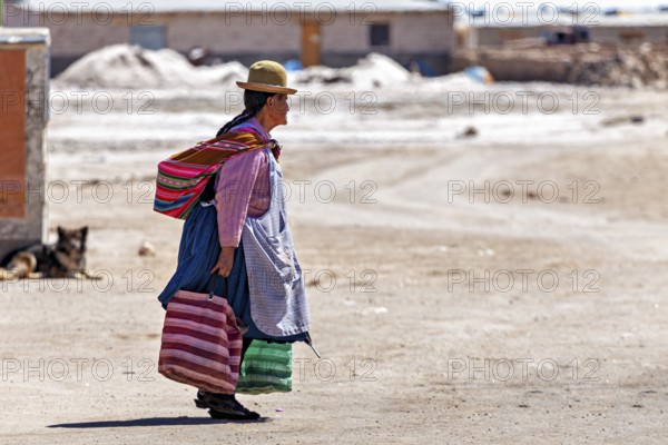 Man in traditional dress walks along a dusty road in a desert landscape, Traditional woman in a village in the Salar de Uyuni in Bolivia