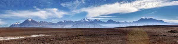 Long mountain range under a clear, cloudy sky in a vast landscape, The landscape with the volcanoes on the Altiplano in Bolivia
