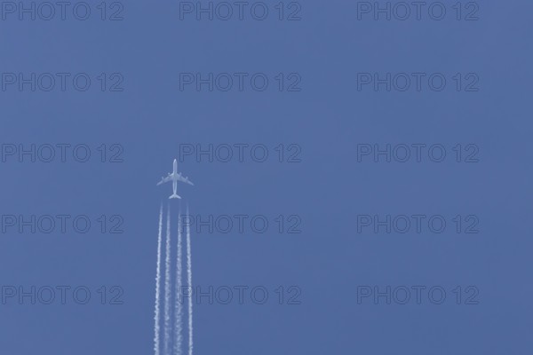 Airbus A340-300 jet aircraft of Lufthansa airlines in flight in a blue sky with vapour trails or contrails behind, England, United Kingdom
