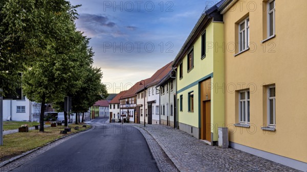 Row of houses in a quiet street with colourful facades and evening sky, the village of Mühlburg in Thuringia near Erfurt