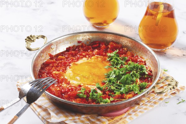 Traditional Turkish dish, scrambled eggs with tomatoes, Menemen, with herbs, in a frying pan, close-up, no people